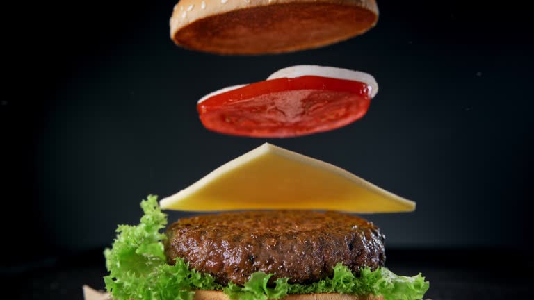 A burger being assembled by dropping all of the components vertically.